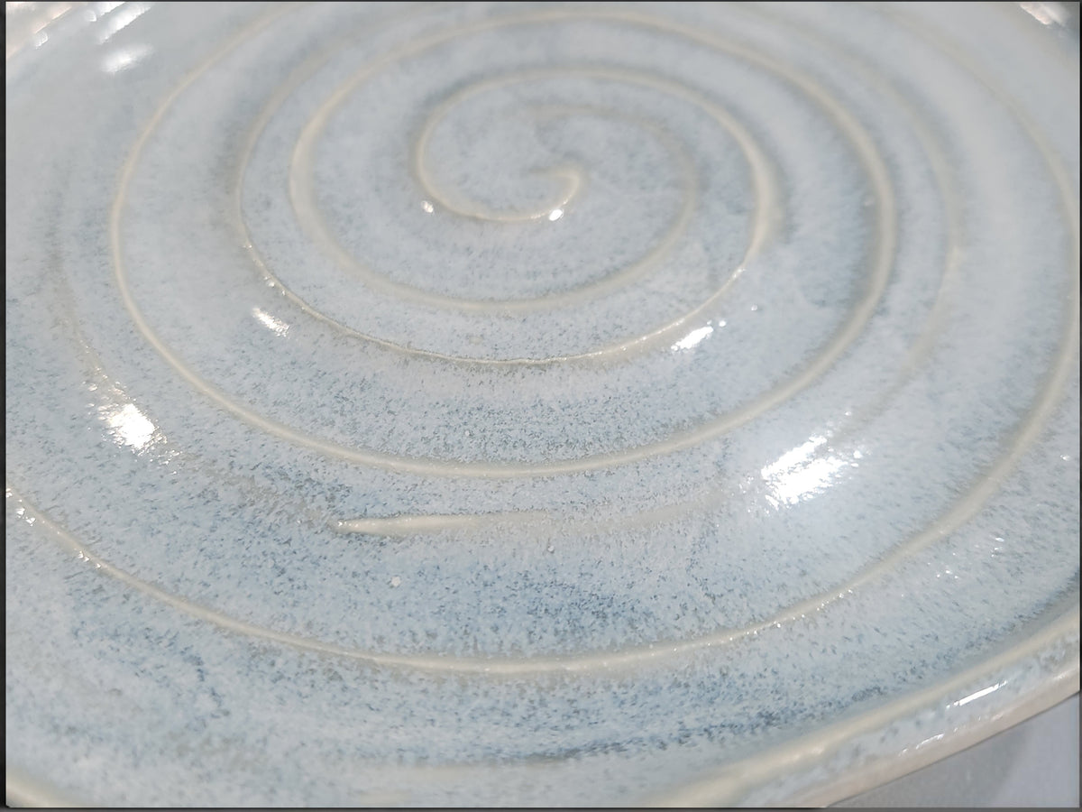 Close-up of softly mottled blue grey glaze and handmade spiral detail