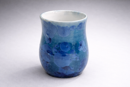 Handmade blue crystalline glaze mug on grey studio background