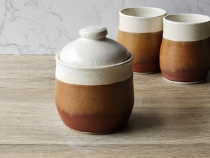 Wheel-thrown pottery container with domed lid and earthy glaze tones