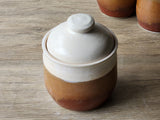 
Australian handmade lidded jar with glossy brown exterior and sculptural form