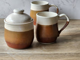 Handmade tall ceramic lidded jar – speckled cream and red-brown glaze – glossy brown interior along side a handmade mug of the same glaze combo