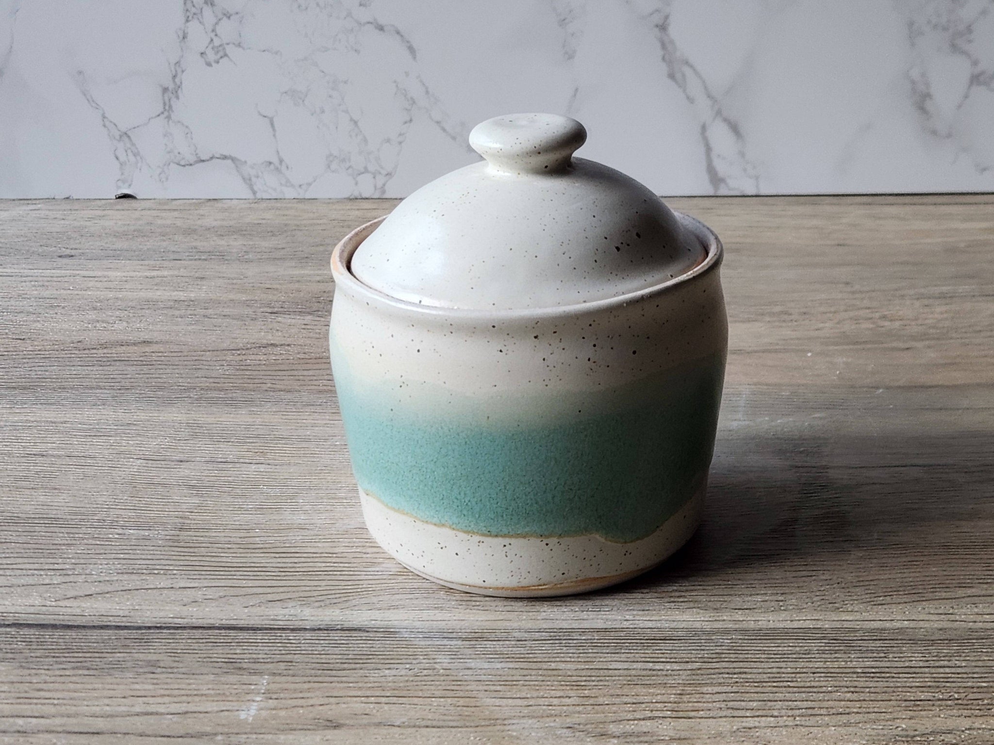 Lidded stoneware jar with soft speckled finish and vertical green accent