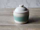 Lidded stoneware jar with soft speckled finish and vertical green accent