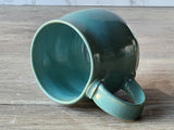 Small Handmade pottery mug in turquoise glaze on the side with internal view