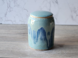 Ceramic jar with blue abstract design on a wooden surface