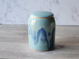 Ceramic jar with blue abstract design on a wooden surface