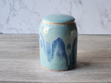 Ceramic canister with blue abstract design on a timber surface