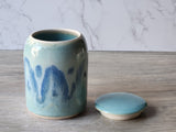 Handmade ceramic containers with blue glaze on a wooden surface.