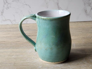 Artisan ceramic tea mug with soft green and blue flecked glaze