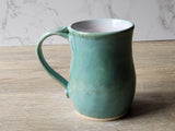 Artisan ceramic tea mug with soft green and blue flecked glaze