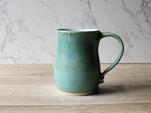 Handmade ceramic mug with rounded shape and comfortable handle