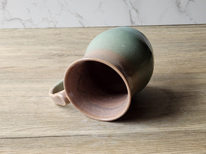 Artisan handmade mug with oatmeal brown interior and green base