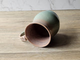 Artisan handmade mug with oatmeal brown interior and green base