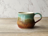 Wheel-thrown ceramic coffee mug in earthy tones