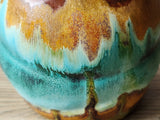 Close up of a Handmade yunomi with aqua and amber glaze layers