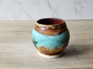 Rustic pottery teacup with aqua and rust gradient
