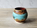Rustic pottery teacup with aqua and rust gradient