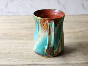 Artisan coffee mug handmade in Australia with turquoise tones  and red browns, with a drippy ash glaze.