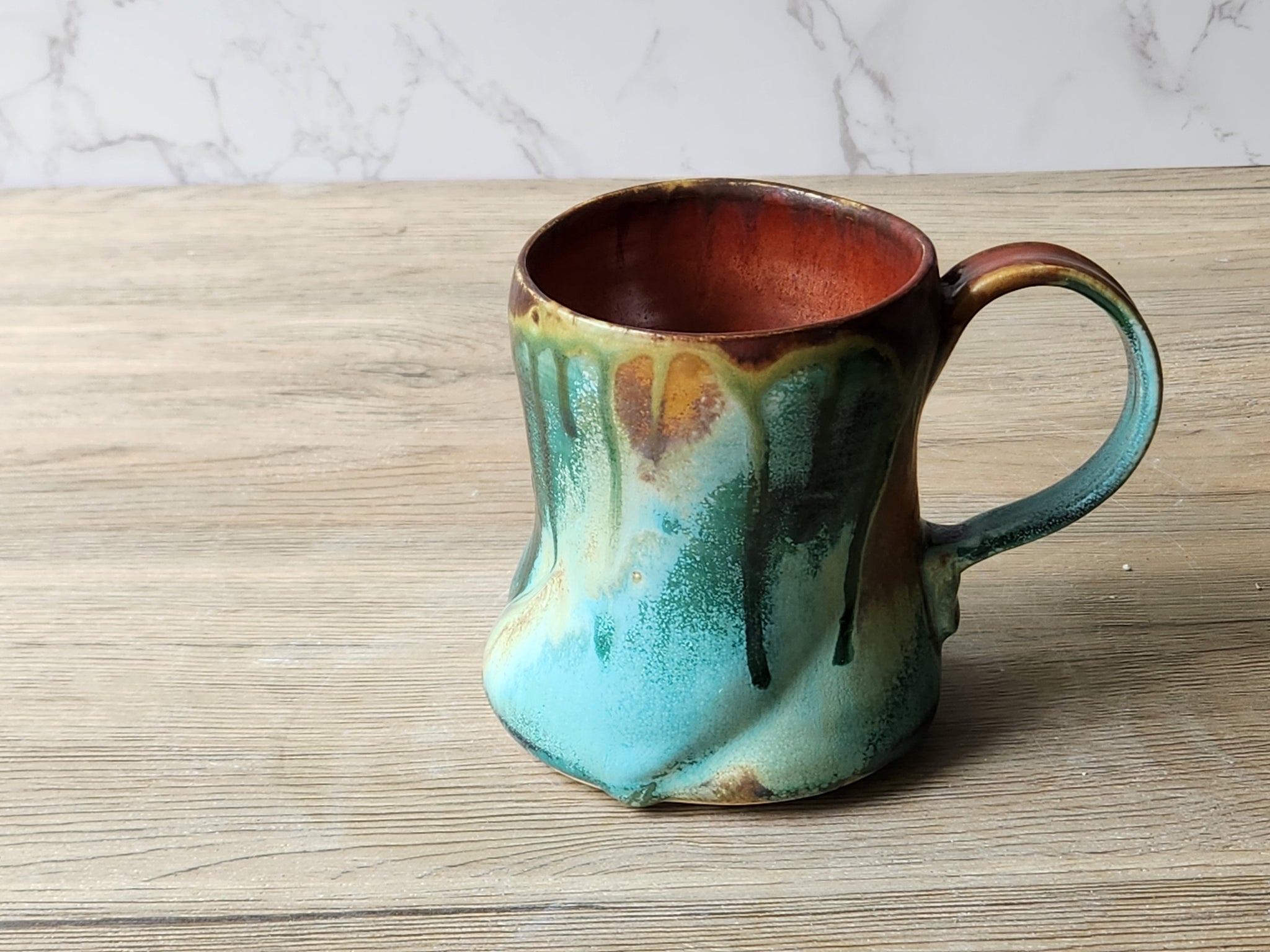 Unique handmade pottery mug with rust red interior