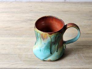 Hand-thrown ceramic mug with earthy green and red glazes