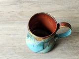 Handmade mug with red ochre interior and teal exterior