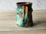 Unique pottery mug with textured surface and thumb indent