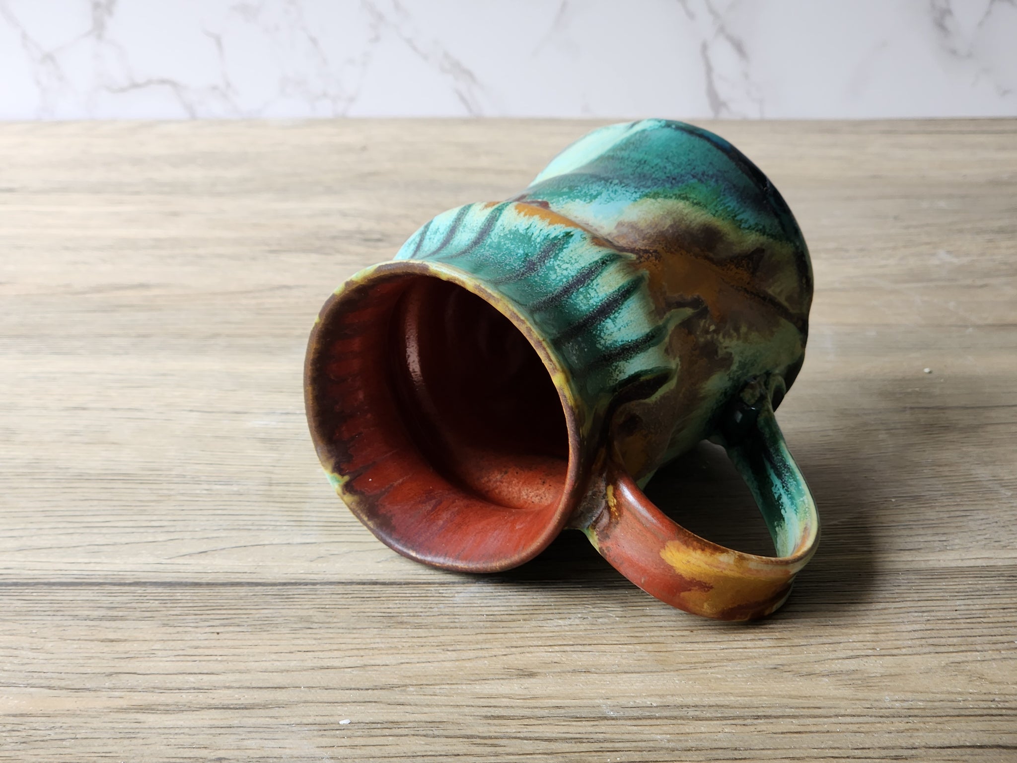 Ceramic mug with flowing multicolour glaze and red interior