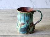 Handmade coffee mug with sculptural handle and flowing glaze