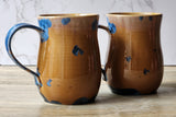 Duo of handcrafted stoneware mugs on wood table