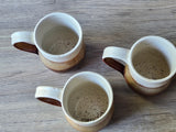 Top view of handmade ceramic mugs showing speckled glazed interiors, stoneware pottery