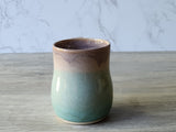 Handmade ceramic mug with soft green and beige glaze, wheel-thrown stoneware pottery