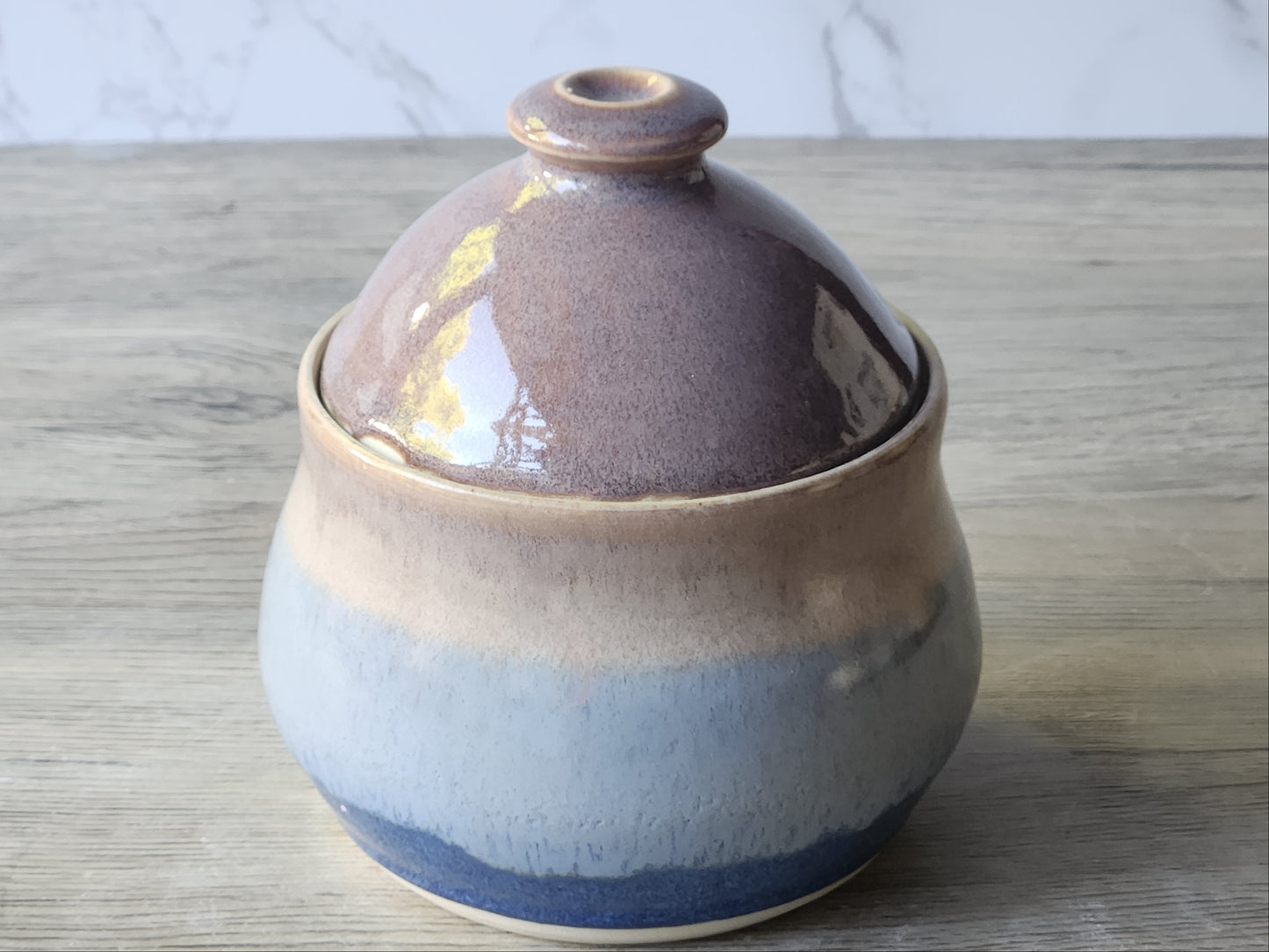 Handmade ceramic sugar bowl and lid displayed separately on kitchen bench
