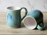 Handmade ceramic mug pair showing interior and exterior blue green glaze”