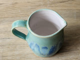 Ceramic milk jug with soft green glaze and natural blue variations