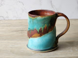 “Stoneware coffee mug with flowing blue and brown glaze, handmade in Australia”