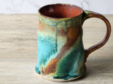 Stoneware coffee mug with earthy turquoise and brown glaze, side view