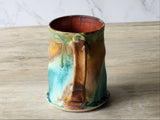 Artisan pottery coffee mug with sculpted handle and natural glaze variation