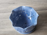Top view of handmade ceramic berry bowl showing blue glazed interior and drainage holes