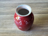 Top angle of glossy red porcelain vase with scattered silver crystal blooms, 17cm tall and 12 cm wide.
