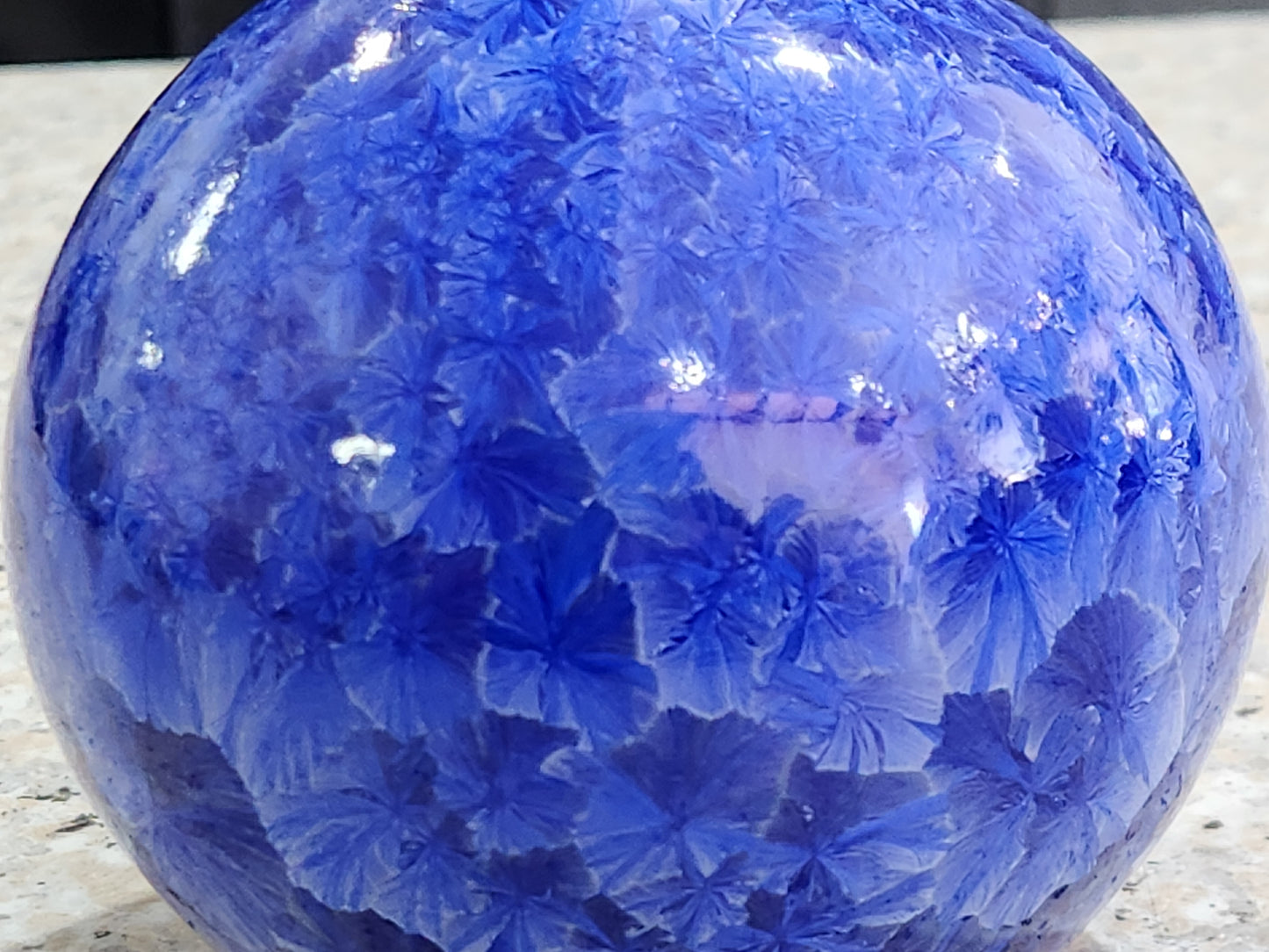Blue crystalline glaze bud vase on warm grey studio background, Buxton Pottery