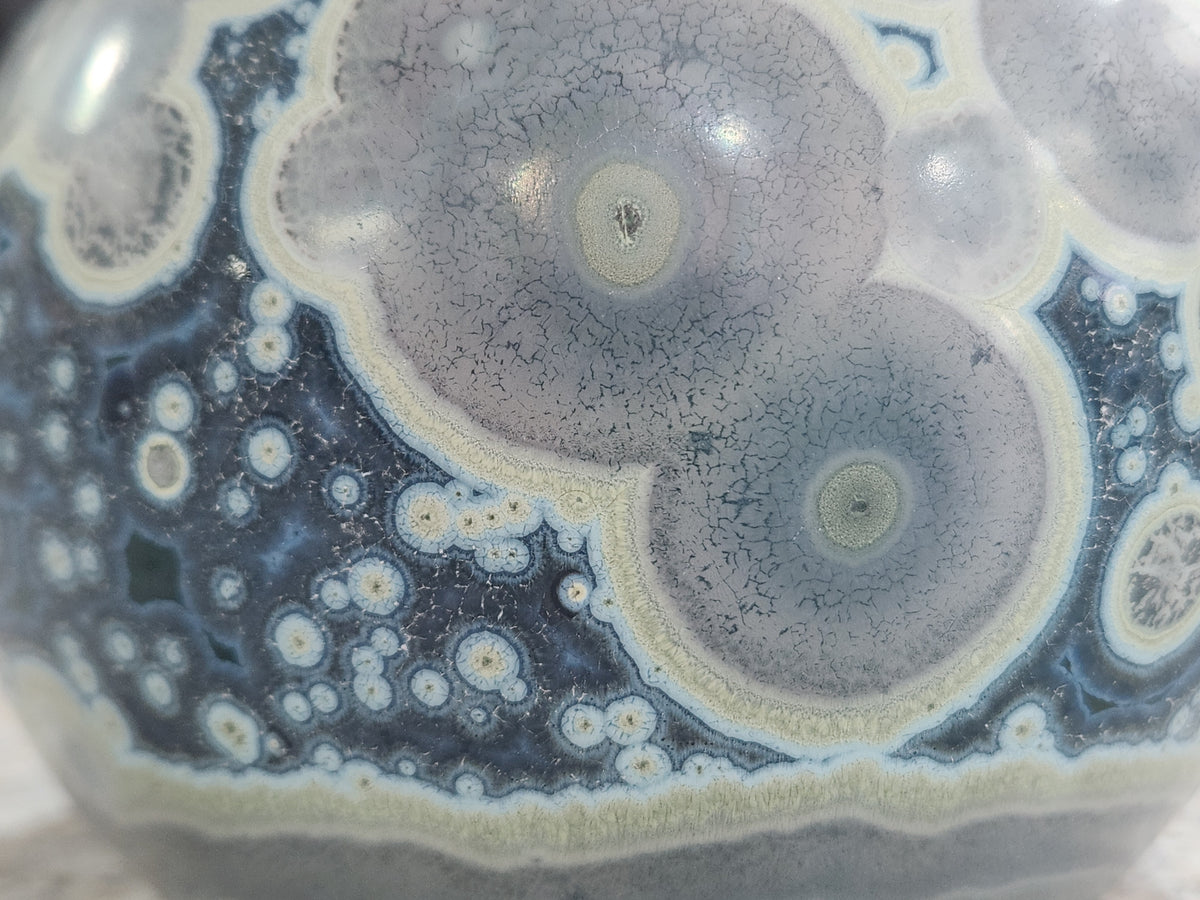 Macro detail of storm-toned crystalline surface with smoky grey and ocean blue glaze patterning