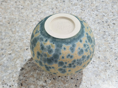 Base view of handmade ceramic vase showing Buxton Pottery stamp and teal crystalline glaze over cream matte background