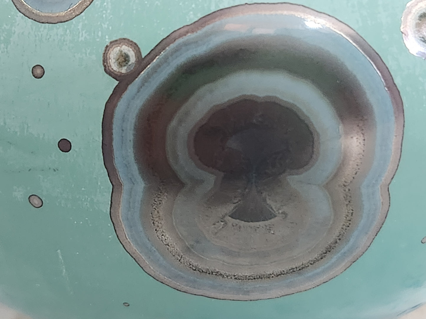 Close up of crystalline ring pattern on teal galaxy glaze handmade ceramic vase