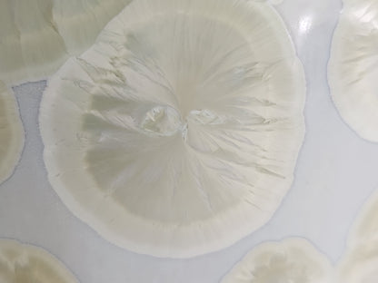 Close up of gold crystalline bloom on white ceramic vase handmade pottery