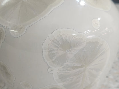 Close up of crystal formation outside  of white handmade ceramic vase