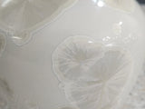 Close up of crystal formation outside  of white handmade ceramic vase