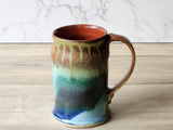 Wheel-thrown pottery mug with earthy drip glaze and warm rust interior