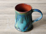 Close-up of mug rim and rust-coloured interior glaze on handmade pottery mug