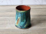 Front view of handmade pottery mug showing flowing glaze drips and colour variation
