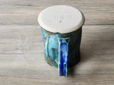 Close-up of handle detail  and bottom on handmade ceramic mug, glossy green teal glaze